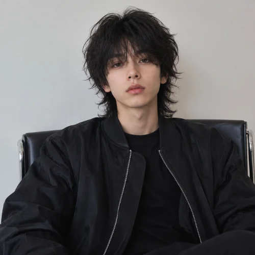 Front view of a man with a messy wolf cut hairstyle sitting on a chair